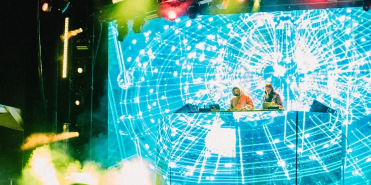 A DJ duo performing under coloured blue, green and red stage lighting at a live venue, representing the Brampton Punjabi live music scene