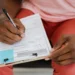 A person completing an OCI application and Indian passport form, representing the New Zealand application process