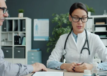 A doctor consults with a patient in a clinic office, illustrating UAE family health insurance outpatient cover