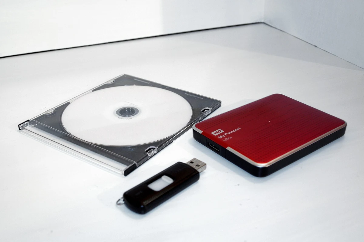 DVD, USB flash drive and external hard drive on a white surface