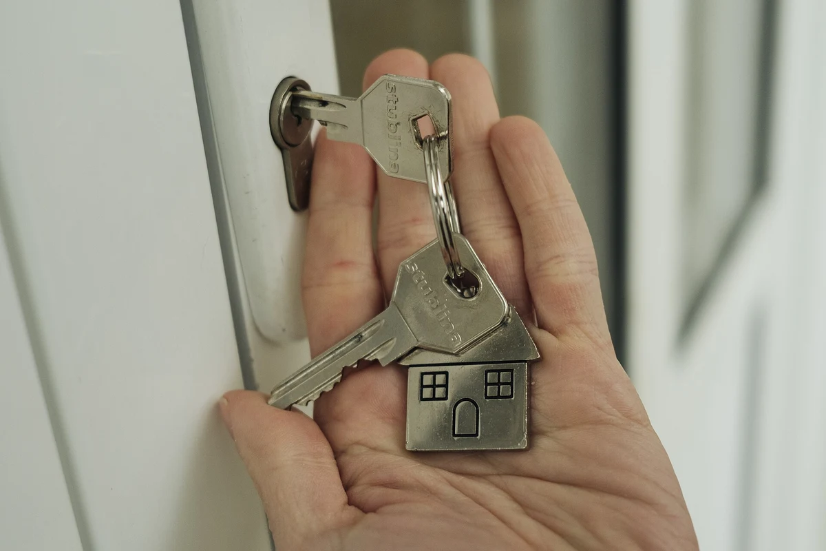 Hand holding keys beside a door lock