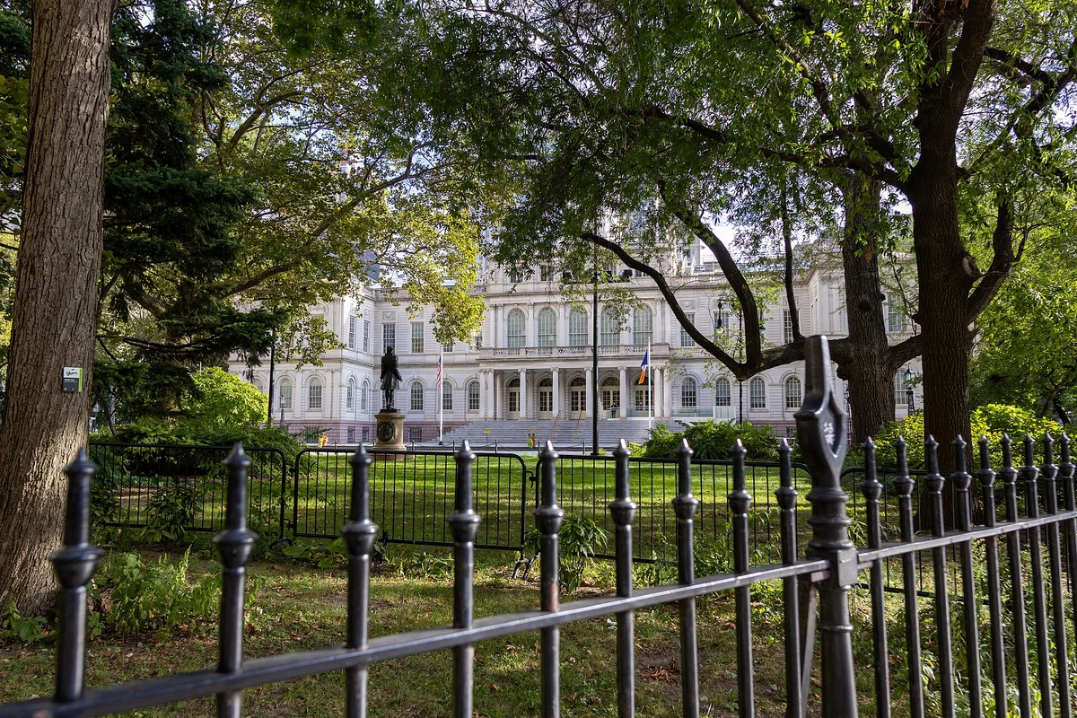 New York City Hall viewed through trees and iron fencing