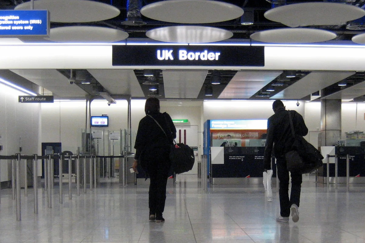 Travellers walking towards the UK Border passport control at Heathrow Airport